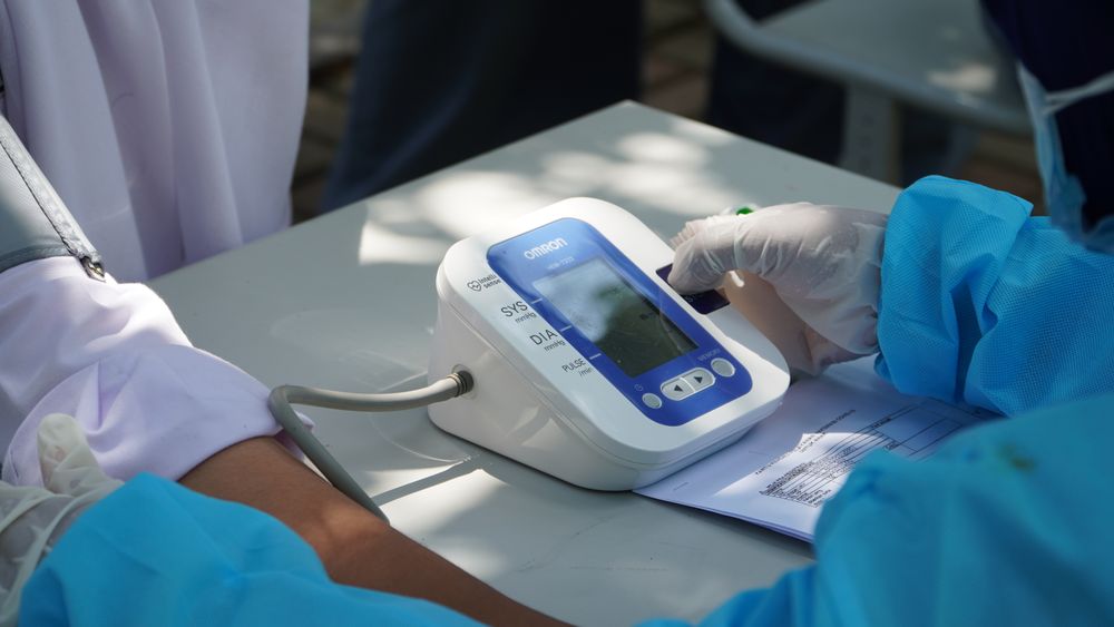 Healthcare worker checking a patient's blood pressure with a digital monitor